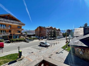 Ein Hotel mit Holzfassade, Parkplatz und freiem Blick auf die Berge im Hintergrund.