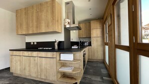 A modern kitchen with wooden cabinets, a black countertop, and a built-in stove. - Résidence la Ménandière W1 (Alpe d'Huez)