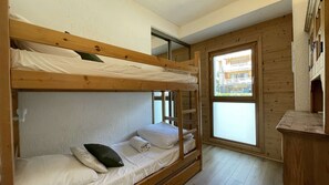 Ein Schlafzimmer mit Etagenbetten, einem Fenster und einem Holztisch.