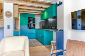 A modern kitchen with teal cabinetry, a black stove, and a wooden ceiling.