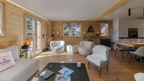A cozy cabin interior with wooden walls, a dining area, and a kitchen. - Chalet La Pavicha - Luxuous Chalet La Pavicha (Huez)