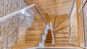 A modern interior with a wooden ceiling, stone wall, and a staircase with white railings. - Chalet La Pavicha - Luxuous Chalet La Pavicha (Huez)