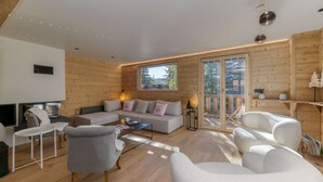 A cozy living room with a sofa, chairs, a coffee table, and a fireplace. - Chalet La Pavicha - Luxuous Chalet La Pavicha (Huez)