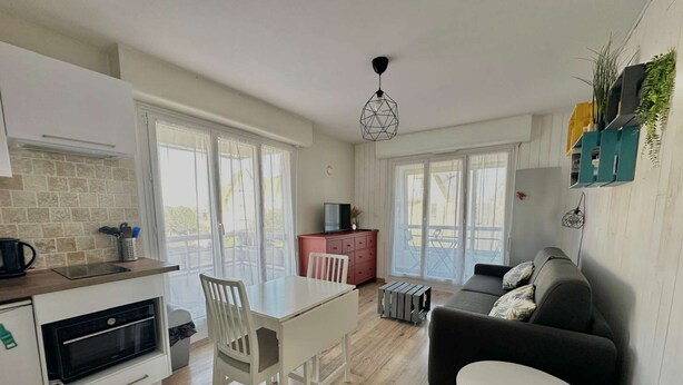 A modern kitchen with a dining area, a sofa, and a small table. - Le petit Courseulles - between port and sea (Courseulles-sur-Mer)