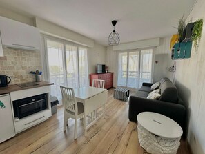 A modern kitchen with a dining area, a sofa, and a small table. - Le petit Courseulles - between port and sea (Courseulles-sur-Mer)