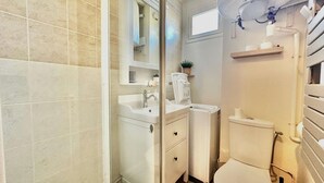 A bathroom with a shower, sink, toilet, and a mirror above the sink. - Le petit Courseulles - between port and sea (Courseulles-sur-Mer)