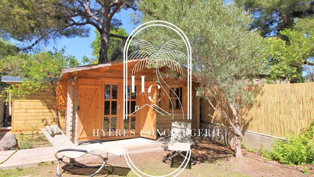 A wooden cabin with a large window, a door, and a small porch area. - Les Grillons-Pieds dans l'eau-Beau Rivage (Carqueiranne)