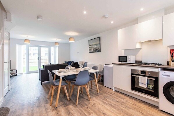 A modern kitchen with a dining area, built-in appliances, and a view to the outside.