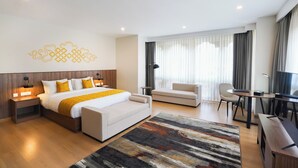Een moderne hotelkamer met een groot bed, een bank, een bureau en een televisie.