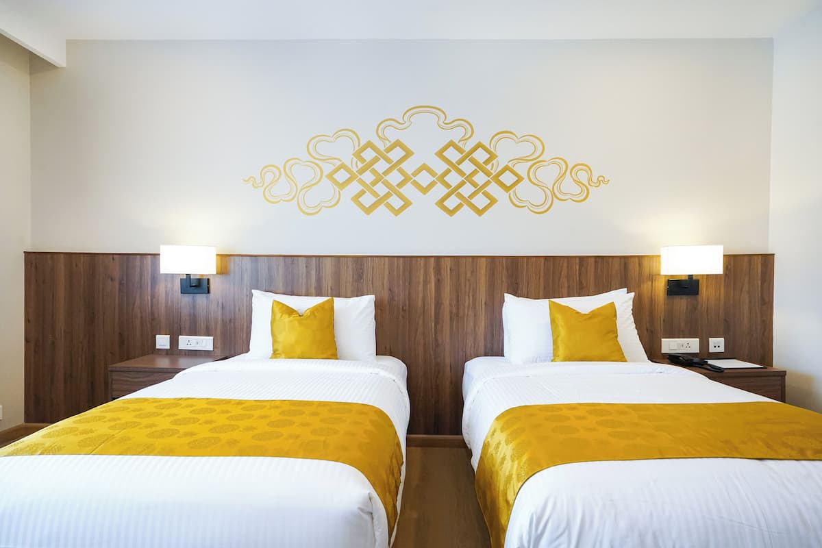 Ein Hotelzimmer mit zwei Betten, einem Holzkopfende, weißer Bettwäsche und einem dekorativen Wanddesign.