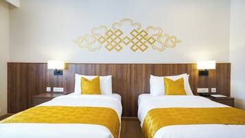 A hotel room with two beds, wooden headboard, white bedding, and a decorative wall design.