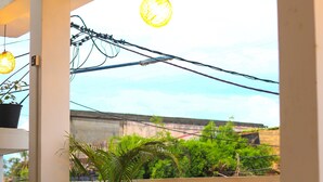 An outdoor dining area with tables and chairs, a potted plant, and a view of the surrounding area. - Royal Hub (Negombo)