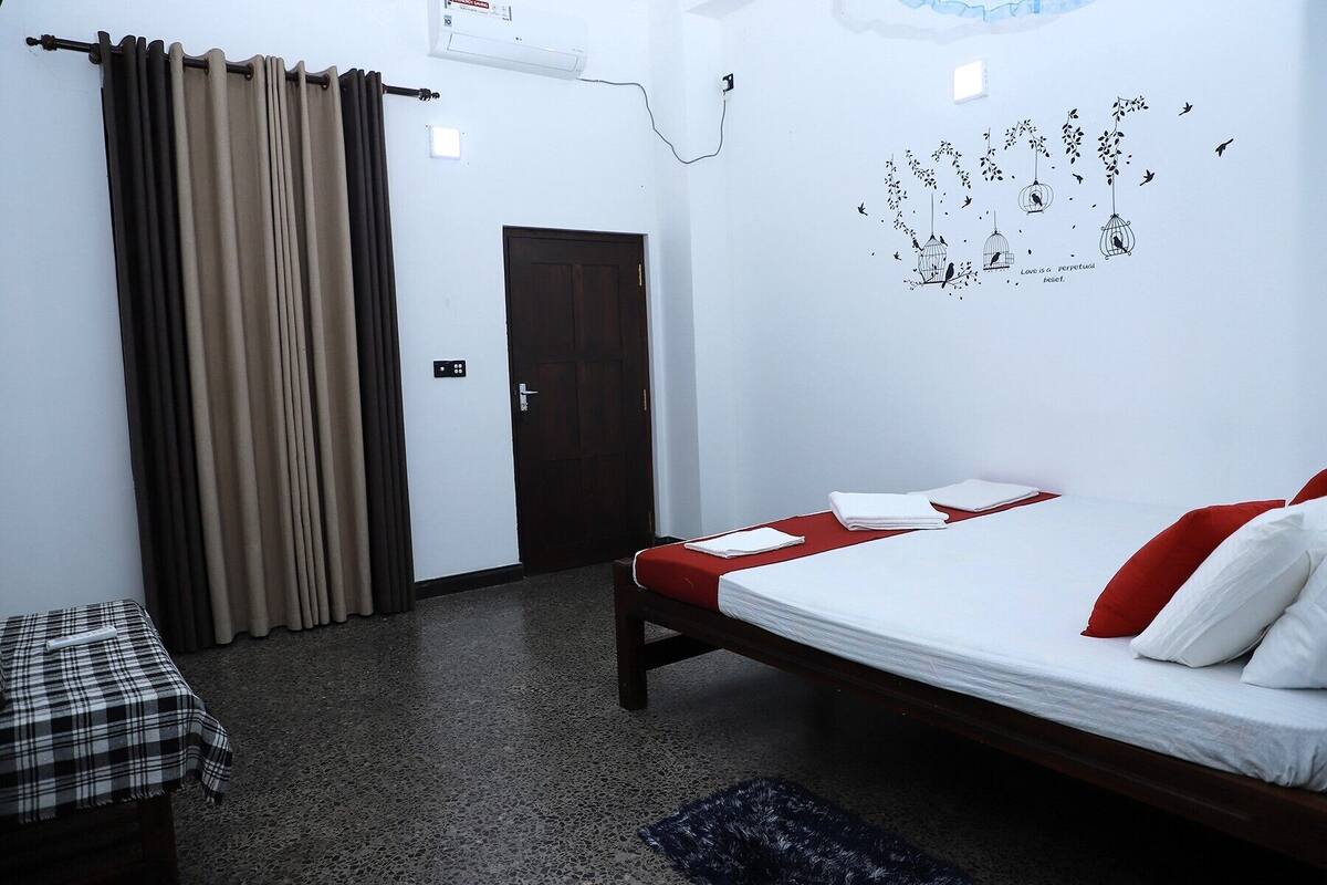 A bedroom with a bed, a bench, a door, and a wall with a bird decoration.