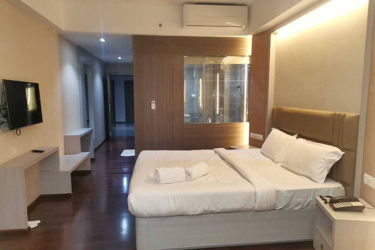 Ein modernes Hotelzimmer mit einem großen Bett, Nachttischen, einem Fernseher und einem Spiegel.