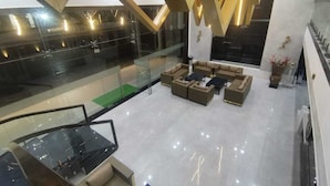 Un hall d’entrée moderne avec un mur en verre, un espace détente avec des canapés et un escalier.