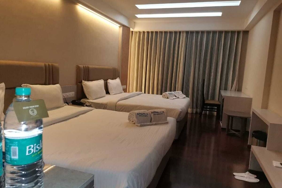 Ein Hotelzimmer mit zwei Betten, einem Schreibtisch, einem Stuhl und einer Wasserflasche.