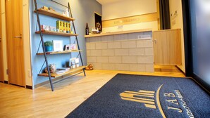 Zona de recepción de hotel con un mostrador de madera, una barra de recepción y una alfombra azul con un logotipo.