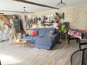 A cozy living area with a blue sofa, a wooden coffee table, and a foosball table.