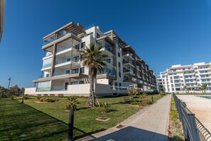 Ein modernes, mehrstöckiges Wohngebäude mit Balkonen, einem gepflegten Rasen und blauem Himmel.