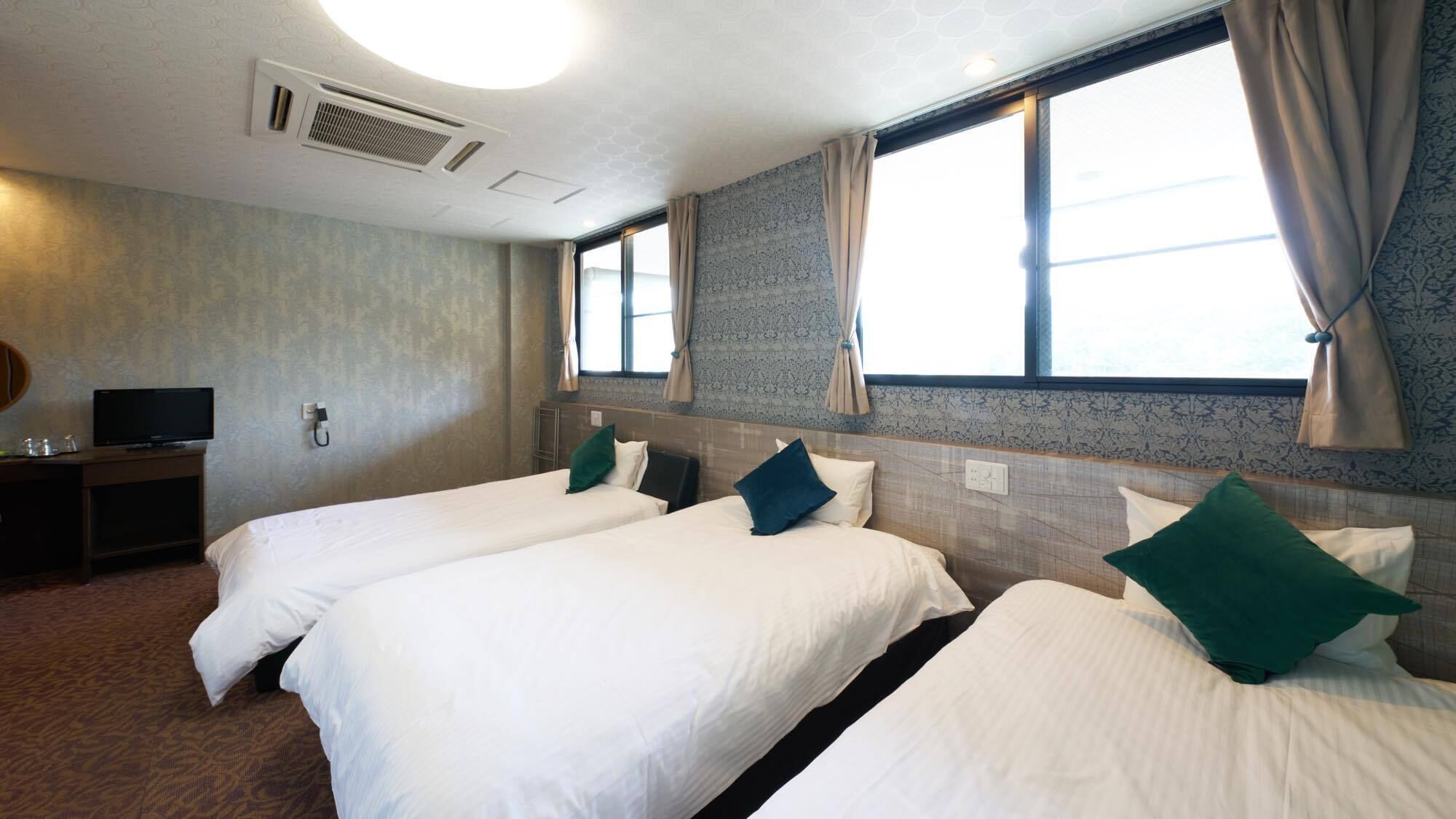 A hotel room with two beds, a TV, and a window with curtains.