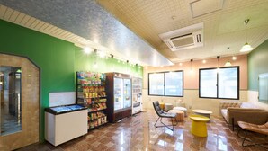 A lobby with a vending machine, seating area, and a large window. - STATION Tajima (Asago)