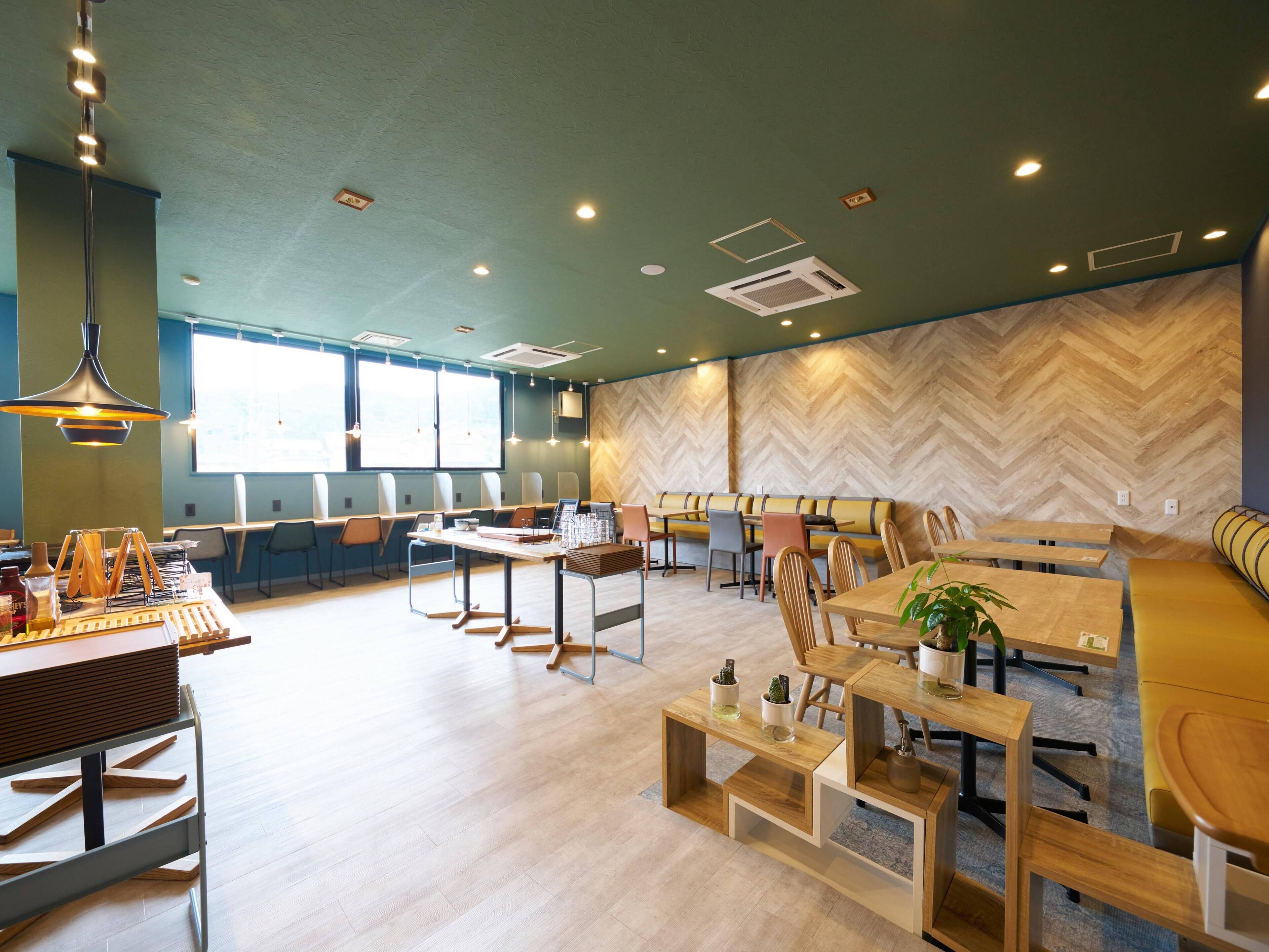 A modern dining area with wooden tables and chairs, a coffee station, and a herringbone-patterned wall.