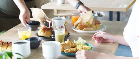 A breakfast setting with a variety of food items and drinks on a wooden table.