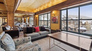 A spacious lounge with a large window offering a view of buildings and snow-covered hills. - Village Hall 09 - 4 Bedroom Residence (Beaver Creek)