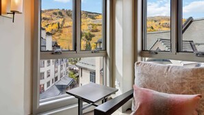A balcony with a view of autumnal hills, a table, and a cushioned bench. - Village Hall 09 - 4 Bedroom Residence (Beaver Creek)