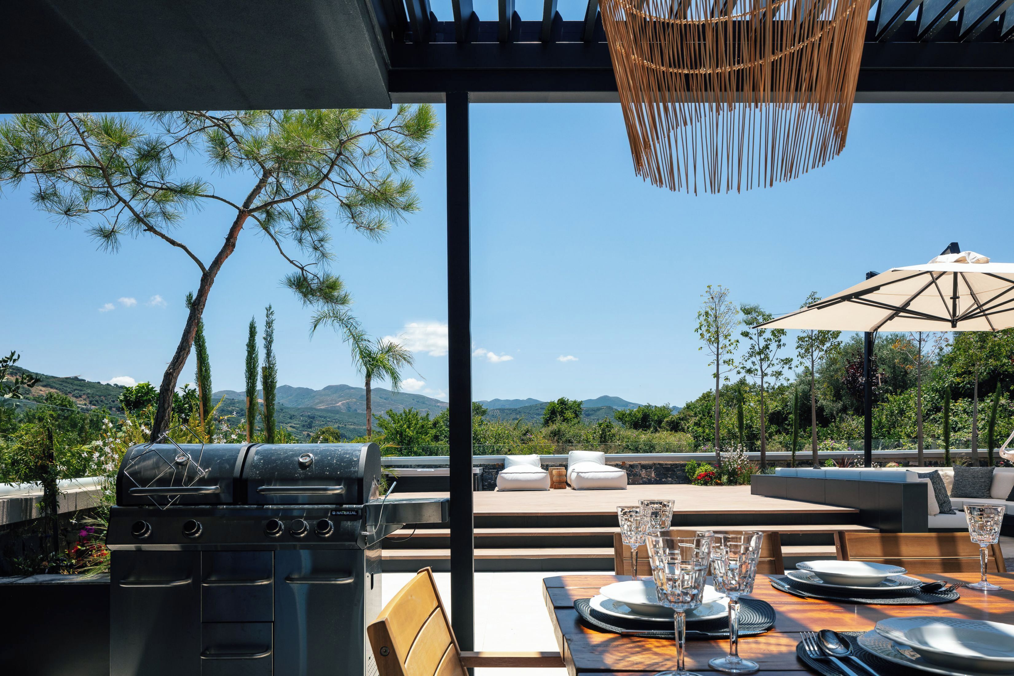 An outdoor dining area with a grill, seating, and a view of the mountains.