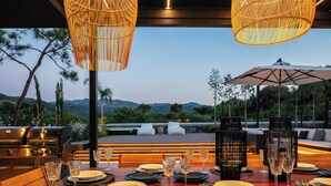 An outdoor dining area with a view of mountains, a grill, and wicker pendant lights. - Casa del Balo - Harmony in Nature by etouri (Chania)