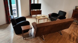 Una sala de estar con un sofá, dos sillones, una mesita de centro, un televisor y un mueble de madera.
