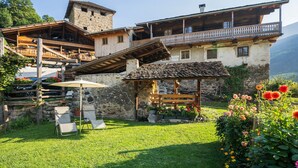 Ein traditionelles Berggasthaus mit Steinaußenwand, Holzbalkonen und einer Terrasse mit Außenbestuhlung.