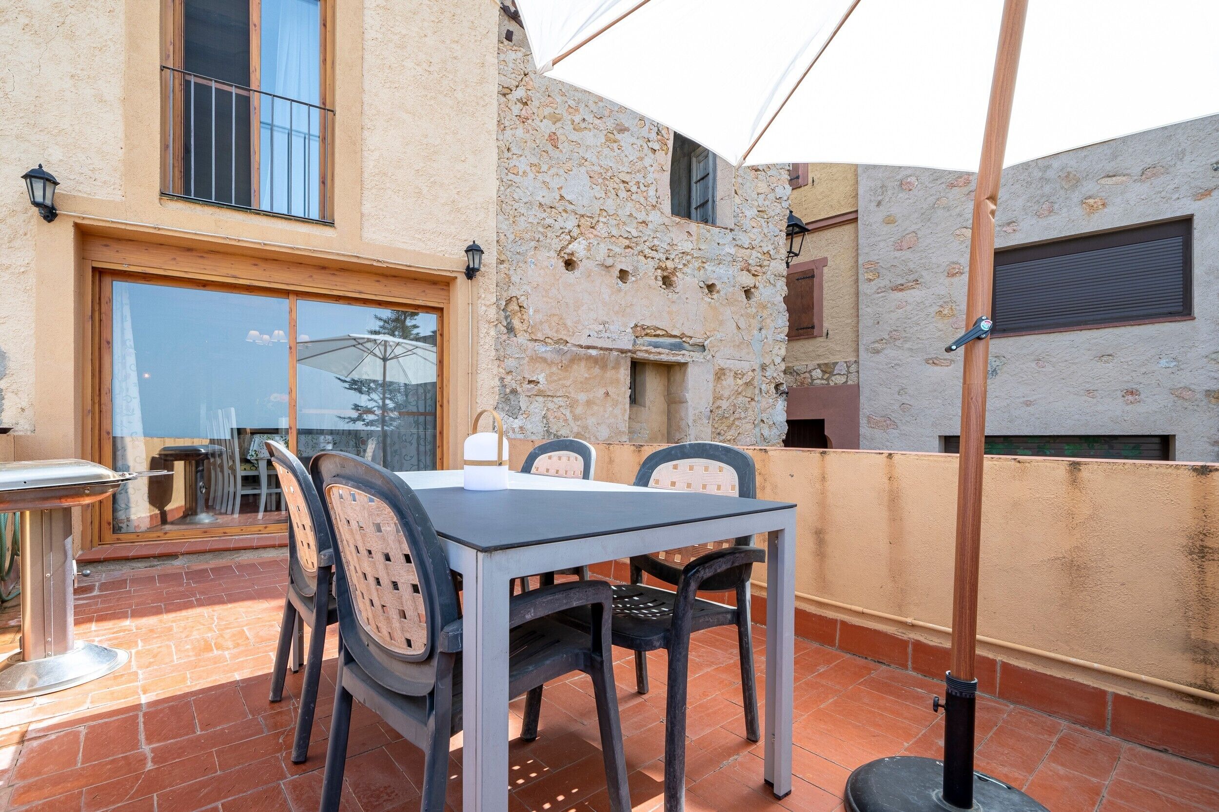 An outdoor patio with a table and chairs, a lamp, and a view of the surrounding buildings.