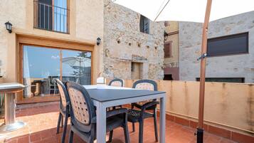 An outdoor patio with a table and chairs, a lamp, and a view of the surrounding buildings.