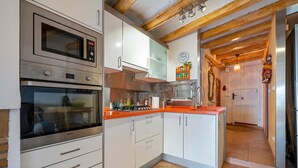 Une cuisine équipée d’appareils électroménagers en acier inoxydable, de meubles blancs et dotée d’un plafond en bois.