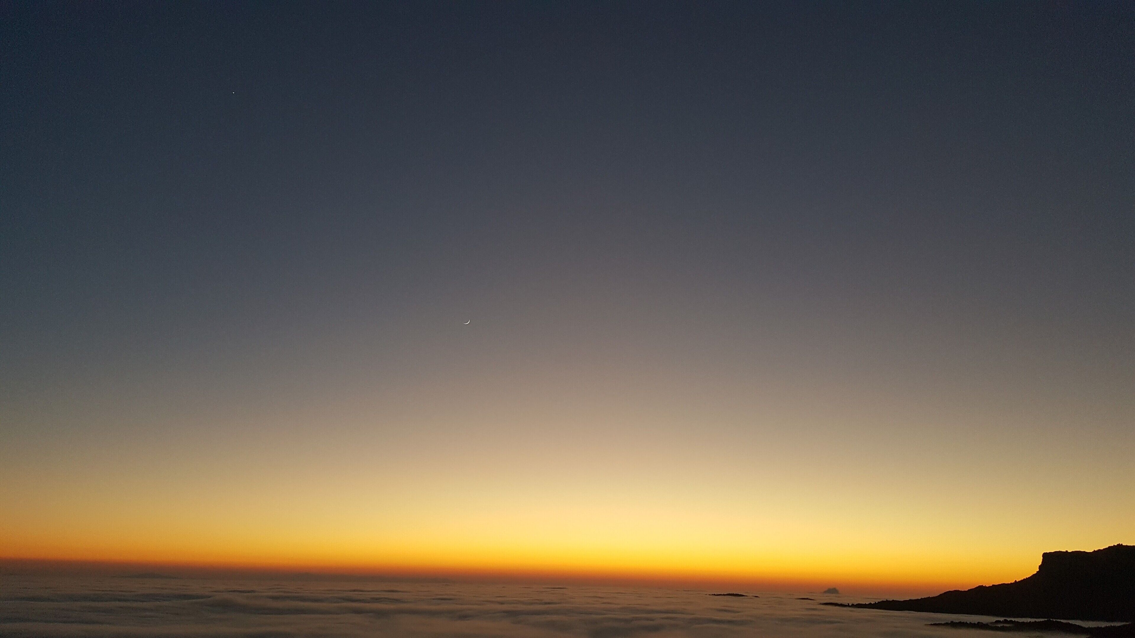 A coastal landscape with a clear sky, a visible horizon, and a distant landmass.