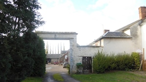 Un sendero estrecho que conduce a un arco de piedra, rodeado de edificios residenciales y vegetación.