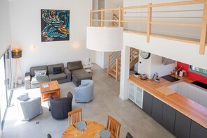 Een modern loft appartement met een hoogslaper, een eethoek, een keuken en een woonkamer.