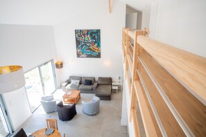 Een moderne woonkamer met een zithoek, een houten trap en een groot abstract schilderij aan de muur.