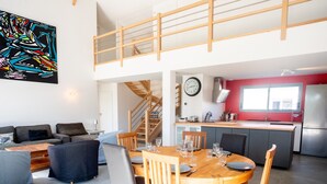 A modern loft-style apartment with a dining area, kitchen, and a staircase leading to an upper level. - Holiday Home 'Villa Surf and Golf' (MESSANGES)