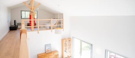 A modern interior with a dining area, wooden furniture, and a loft space.