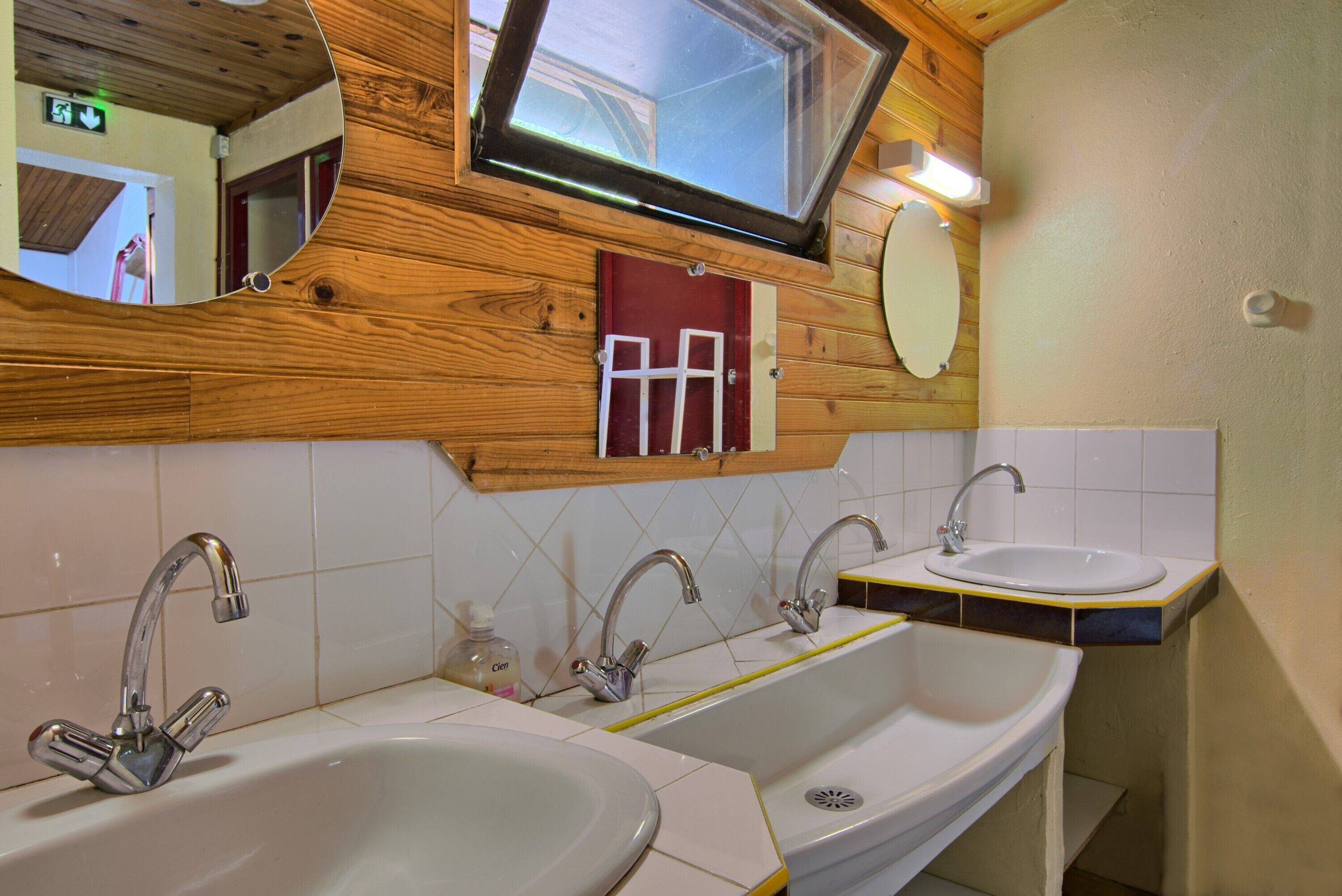 Un baño con dos lavabos, un espejo, un televisor y paneles de madera.