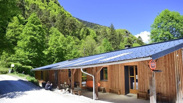 A wooden building with a blue roof, a bench, and a sign. - Skioura Holiday Home, Group Accommodation (Bagnères-de-Luchon)