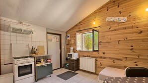 A compact kitchen with a gas stove, oven, microwave, and a small dining area with a table and chair. - Skioura Holiday Home, Group Accommodation (Bagnères-de-Luchon)