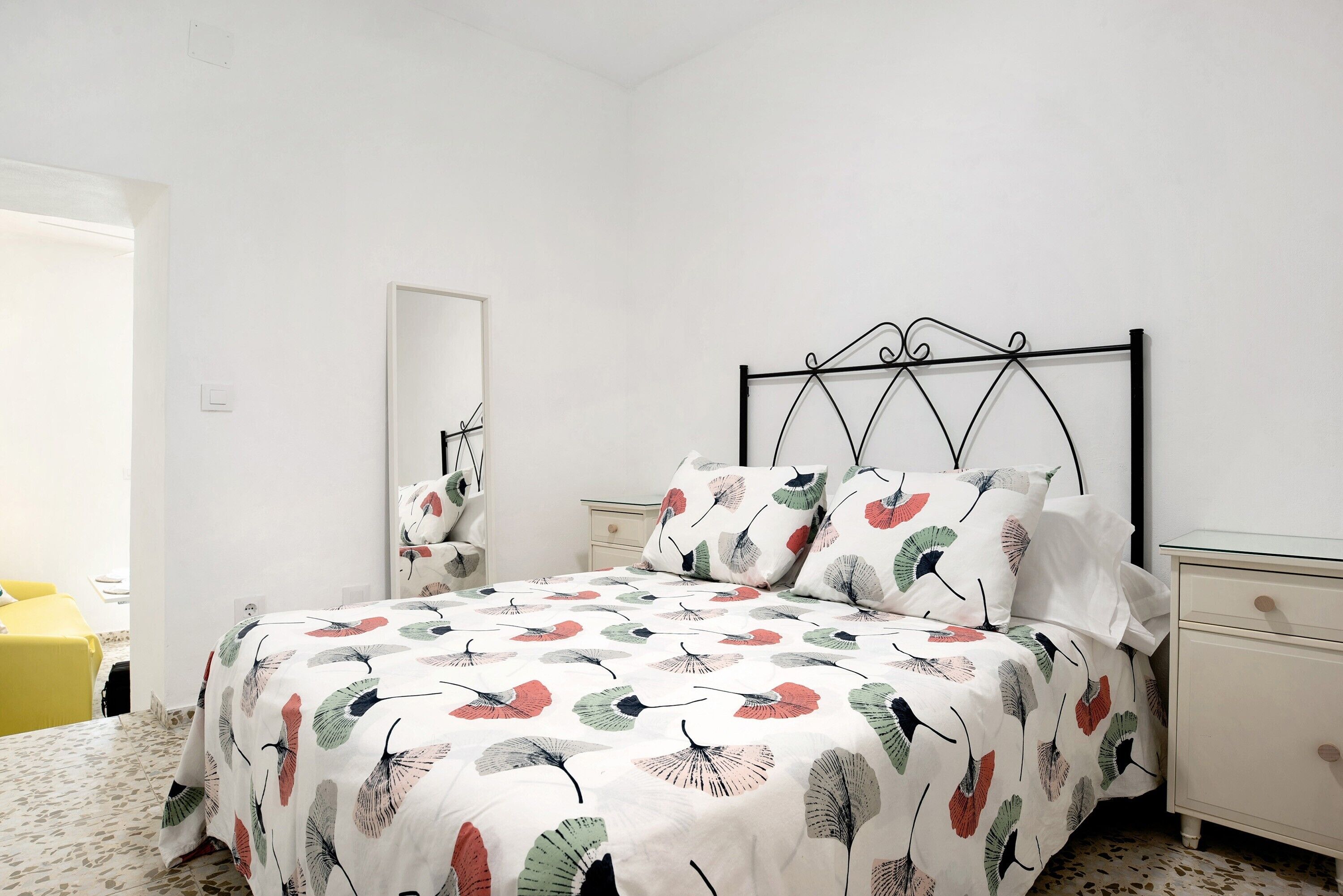 Une chambre à coucher avec un lit, une table de chevet, une commode et un miroir.