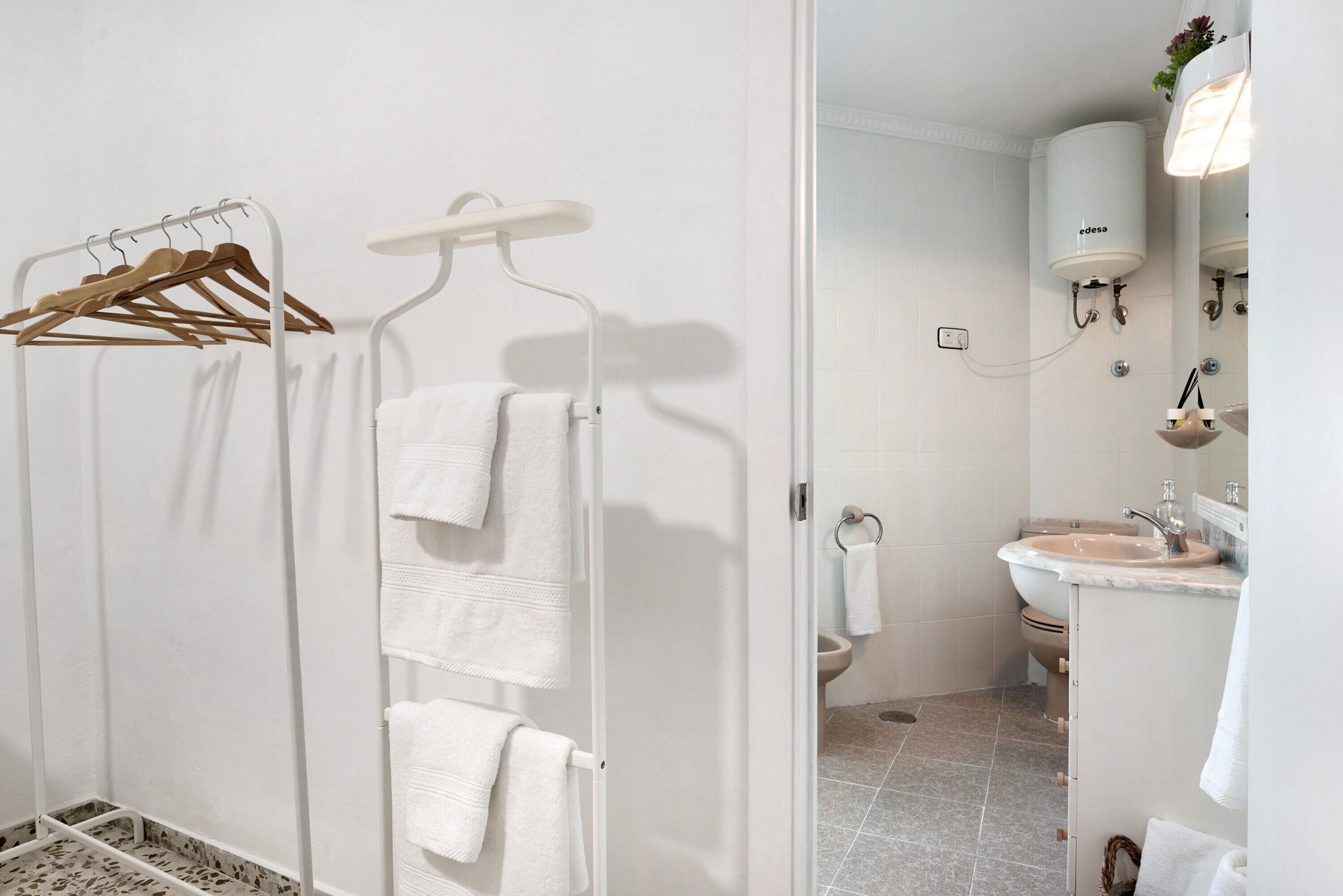 A bathroom with a shower, a sink, and a towel rack.