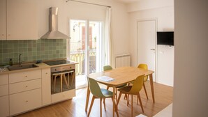 A compact kitchen with a dining area, a built-in oven, and a TV mounted on the wall. - Solemar Sicilia - Casa Britta  (Santa Flavia)