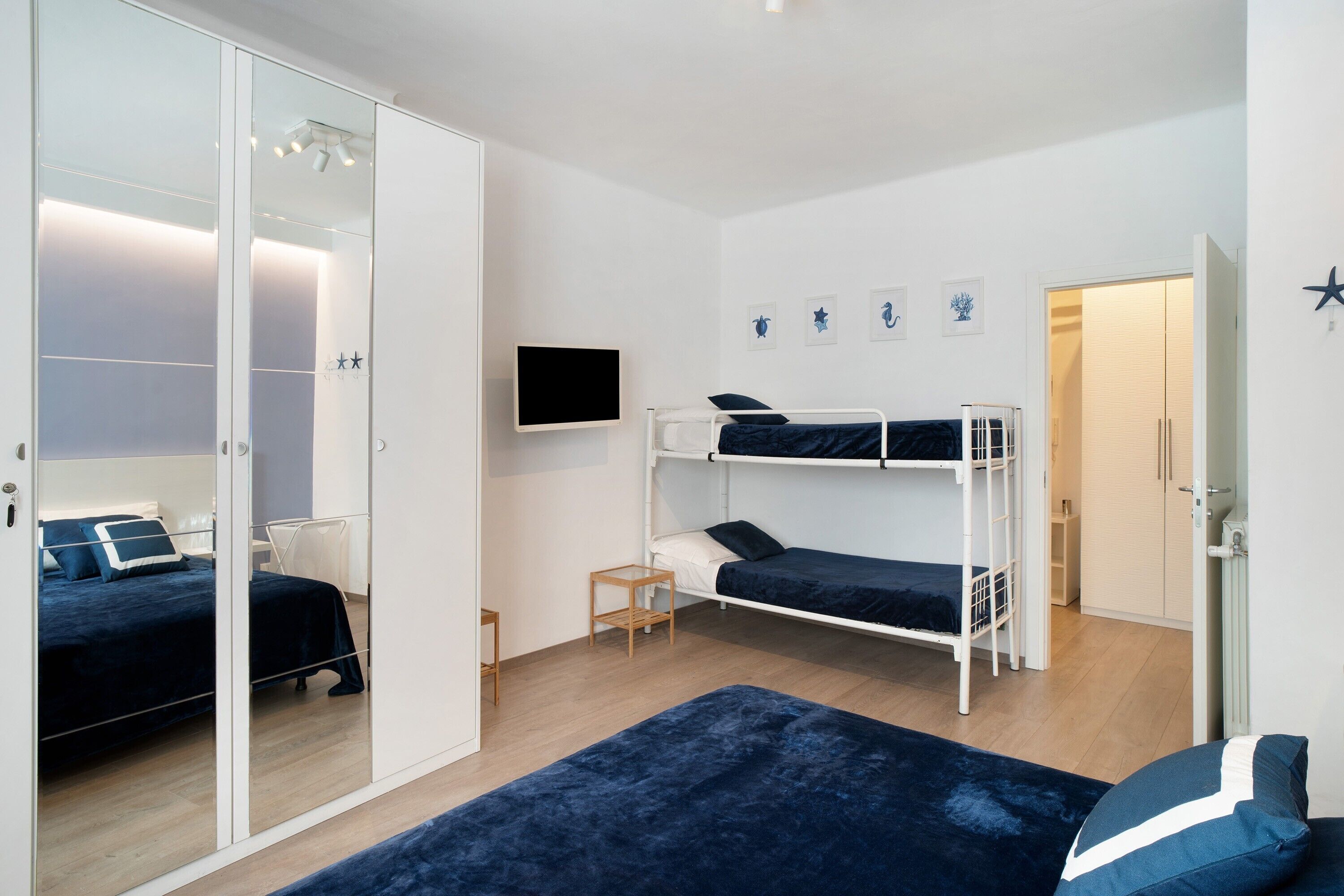 Ein Schlafzimmer mit Etagenbett, einem kleinen Nachttisch, einem Fernseher und einem Kleiderschrank.