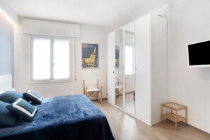 Une chambre à coucher avec un lit, une armoire, une petite table et une affiche accrochée au mur.